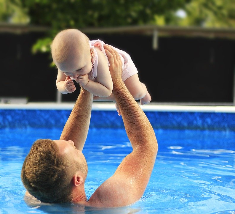 Vader die met zijn baby aan het zwemmen is